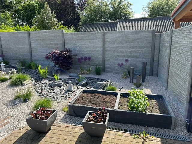 Le bac potager en dalles de schiste et les plantations devant la palissade en béton décoratif.