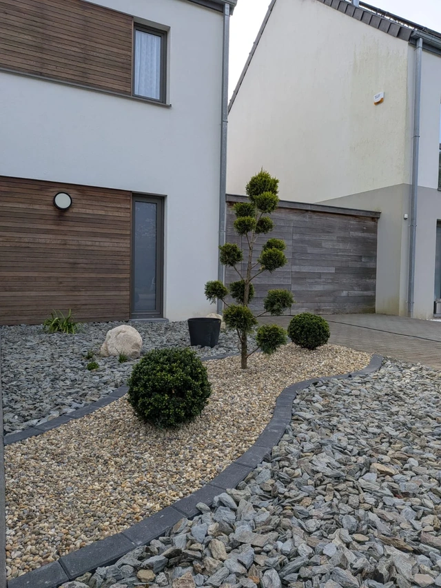 L’arbre en nuages au cœur du parterre de schiste, accompagné d’un chemin décoratif bordé de clinker bleu anthracite.