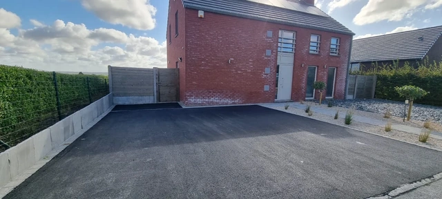 Le parking en asphalte et les plaques de grès sur le côté gauche.