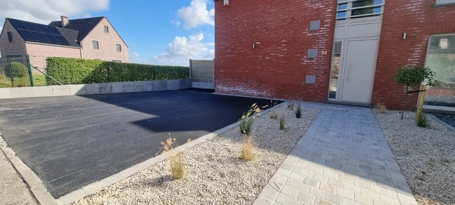 Le parking rejoint l’allée piétonne qui mène à la porte.