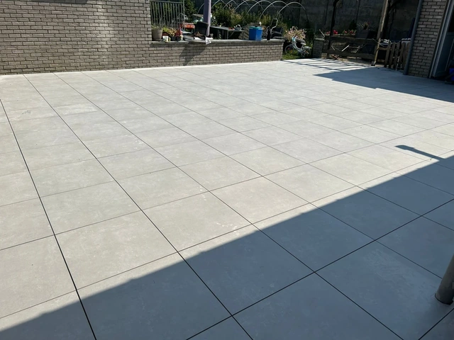 À Ath, une terrasse en céramique claire sur plots.