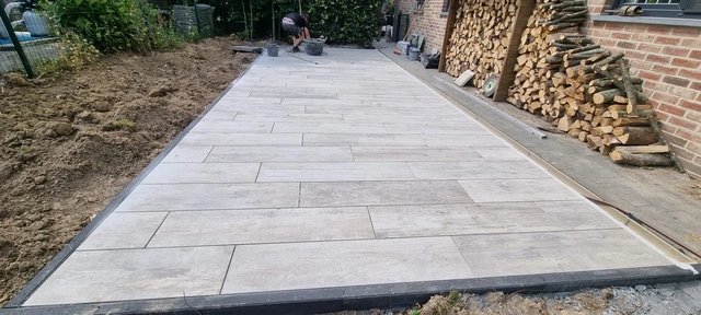 Une terrasse en carrelage imitation parquet, délimitée par des bordures anthracite.