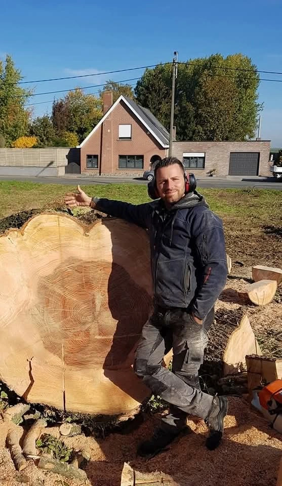 Le dirigeant des Jardins Athois, pouce levé à côté d’un tronc d’arbre sur chantier