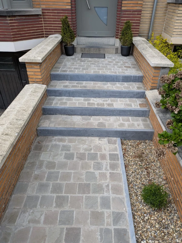 La pierre bleue souligne les contours de l’accès pavé.