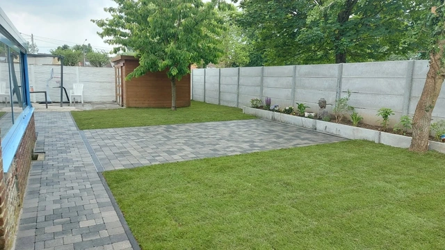 Le jardin terminé : terrasse en clinkers multicolores, pelouse en rouleau et clôtures en béton.