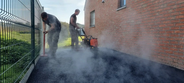 La mise en œuvre de l’asphalte sur le côté de la maison.