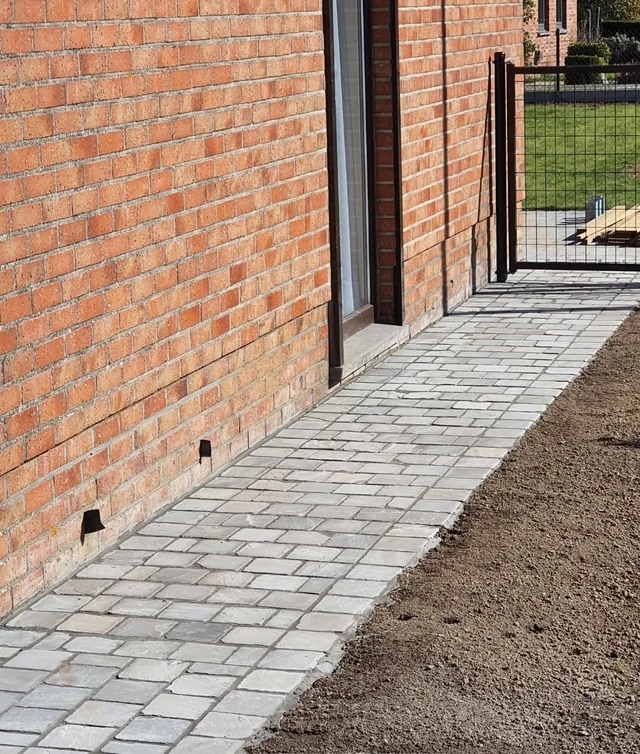 Le pavage longe la façade pour relier les accès de la maison.