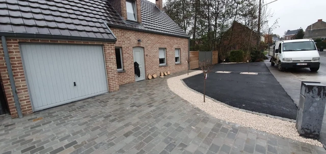 Vue d’ensemble du pavage devant le garage et des zones de parking en asphalte.