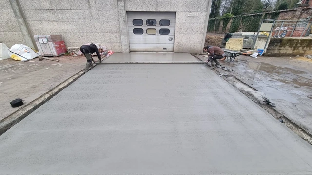 Une dalle en béton coulée devant le garage de l’école de Perwez : un chantier pour une école, qui illustre aussi notre travail auprès des établissements et des administrations.