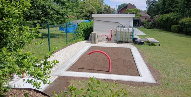 La terre préparée au centre et les gaines prévues avant l’installation de la serre.