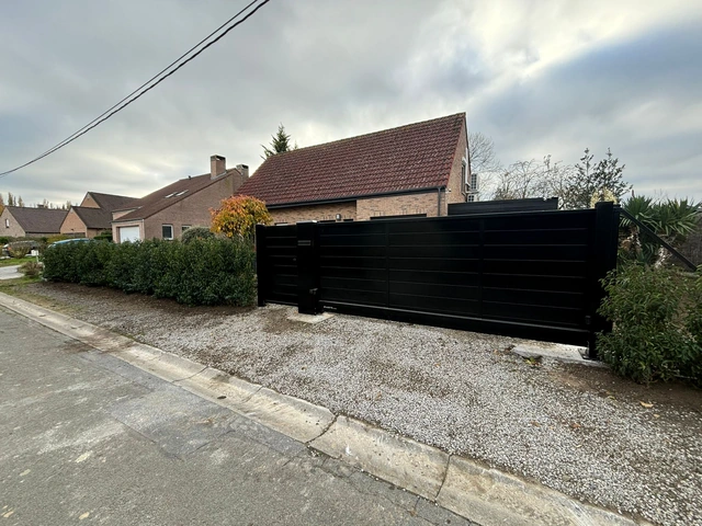 Portail noir et portillon assorti entourés de végétation
