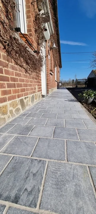 Le nouveau trottoir en pierre bleue souligne la façade.