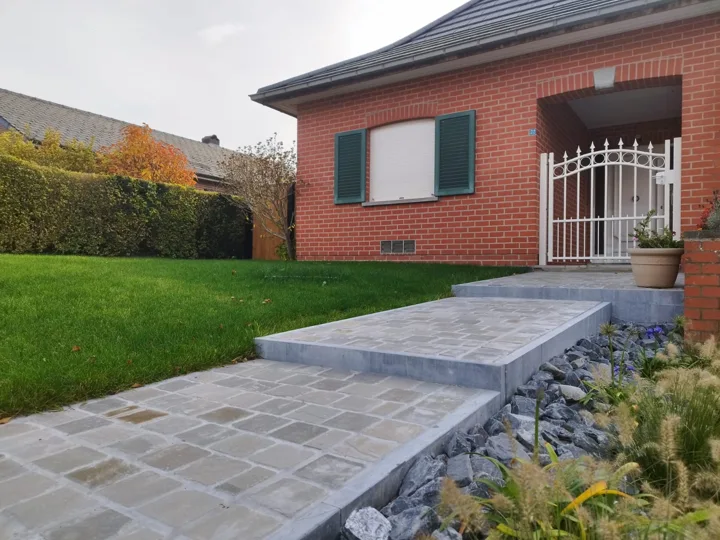 Le chemin pavé rejoint l’entrée de la maison.