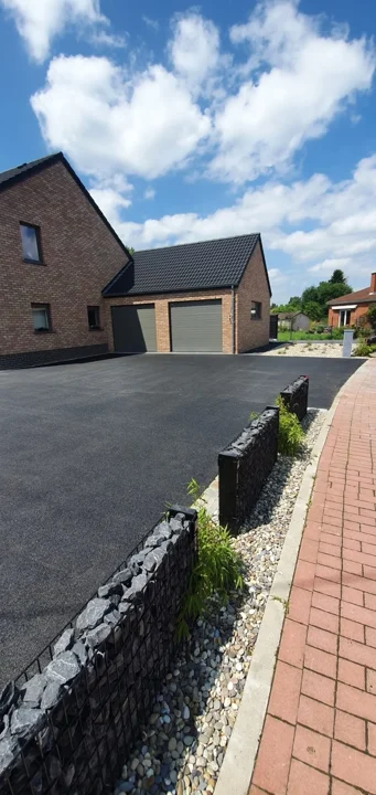 Le parking en asphalte et les gabions bas structurent la devanture.